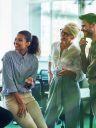 Group of cheerful business people communicating, discussing something and smiling while standing in the modern office or coworking space